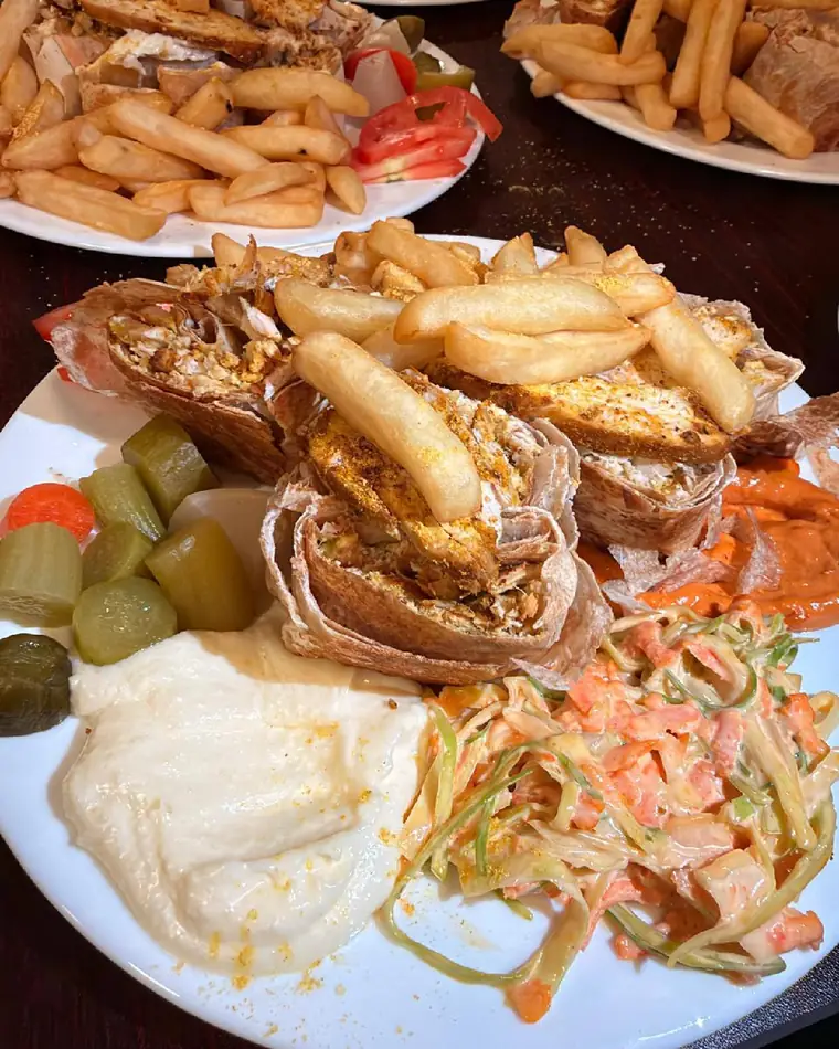 Shawarma wraps topped with fries, with pickles, garlic sauce and coleslaw