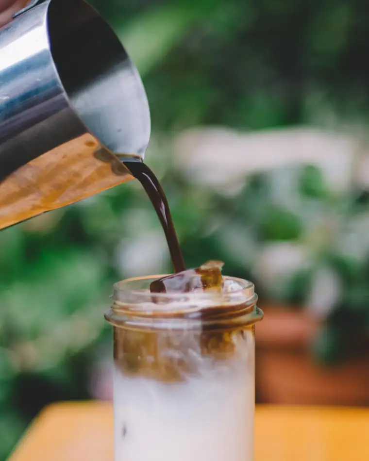Milk poured over an iced coffee